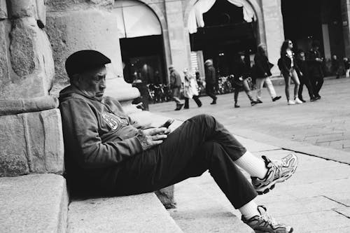 Photo Monochrome D'un Homme Assis Dans La Rue