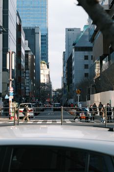 Bustling Tokyo street with skyscrapers and pedestrians on a clear day.