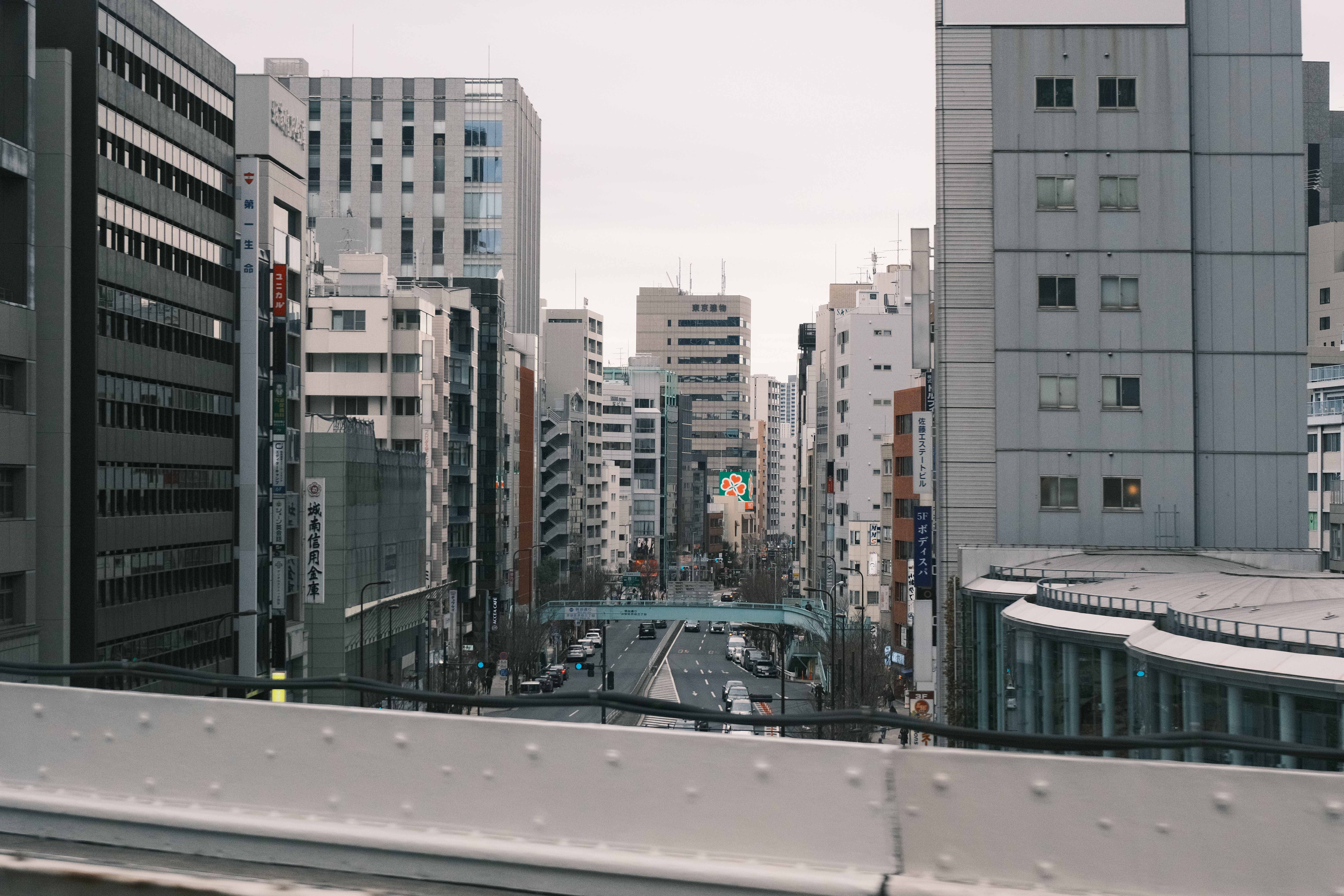 Moody urban street view of Tokyo's towering skyscrapers and bustling city streets.