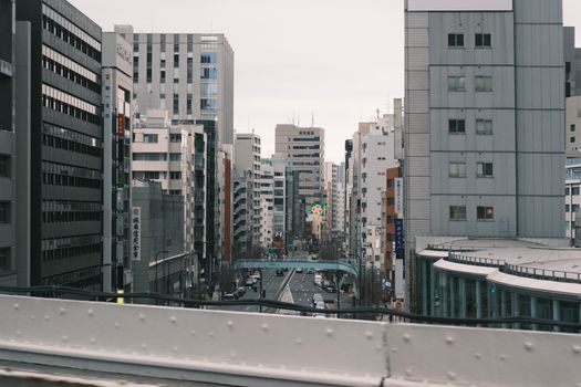 Moody urban street view of Tokyo's towering skyscrapers and bustling city streets.