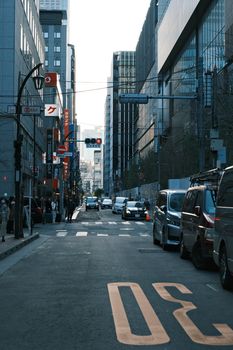 Moody urban street scene in Tokyo with skyscrapers and cars during dusk.