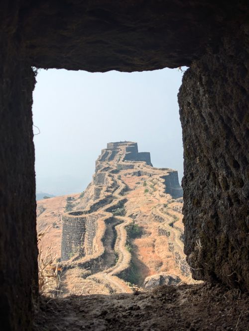 Free A captivating view of a historical Indian fort seen through a stone window, showcasing architectural brilliance. Stock Photo