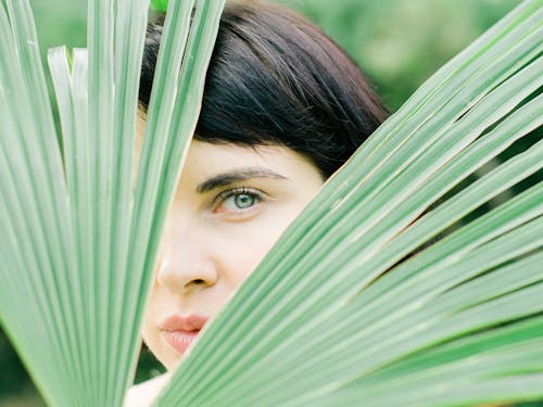 Free Woman Looking Through Palm Leaves Stock Photo