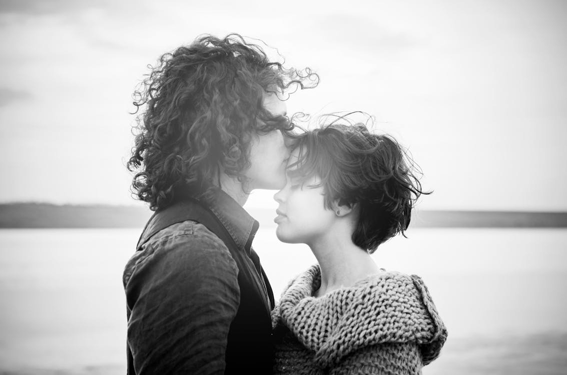 Grayscale Photo of Man Kissing Woman's Forehead