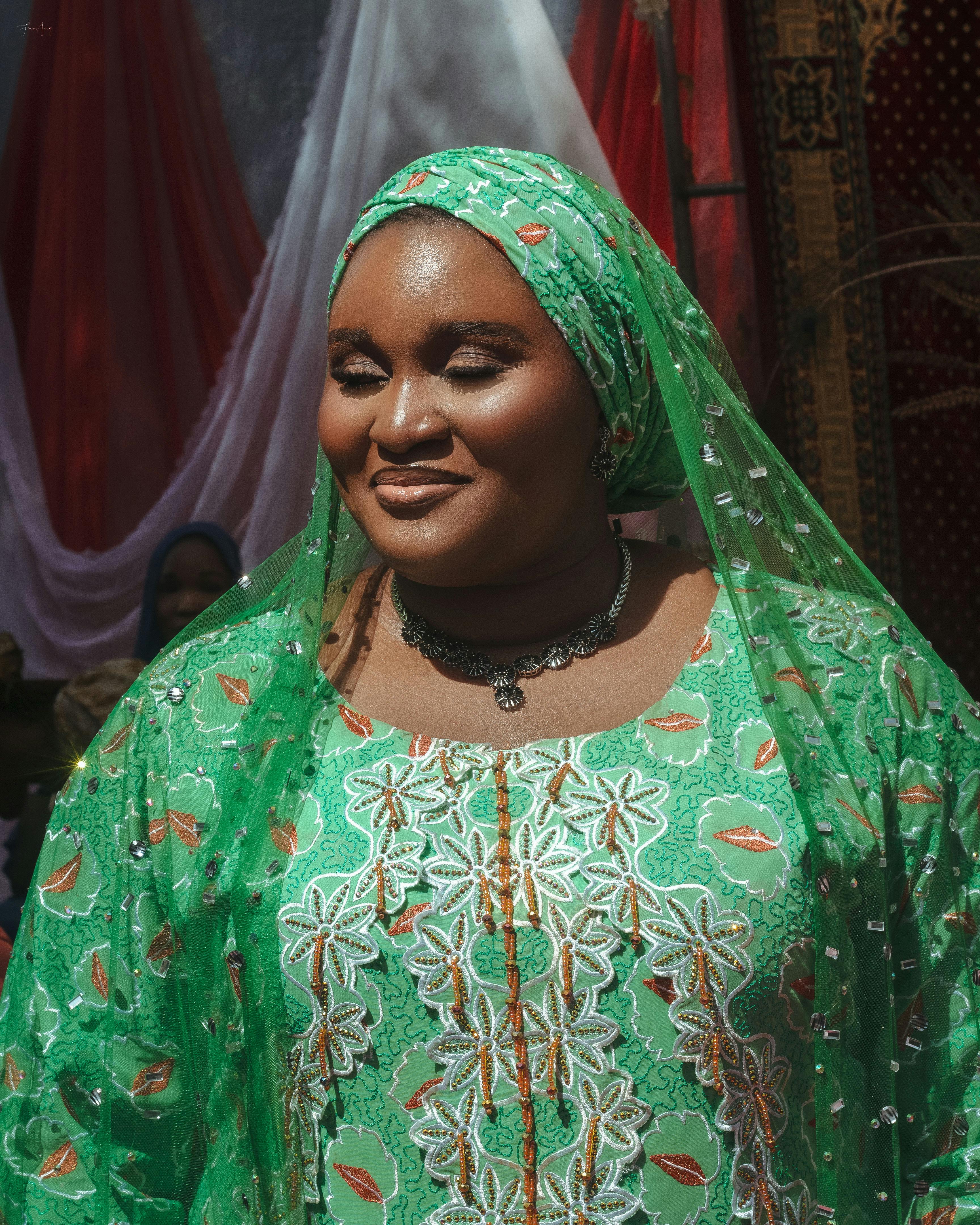 De franc Dona amb un vestit tradicional verd vibrant en un esdeveniment cultural. Il·luminada pel sol i alegre. Foto d'estoc