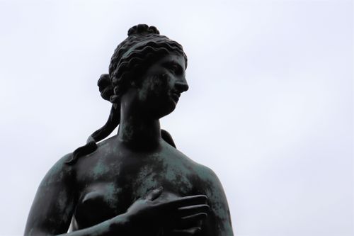 Free Detailed view of a bronze statue with a cloudy sky background, highlighting classic artistic expression. Stock Photo