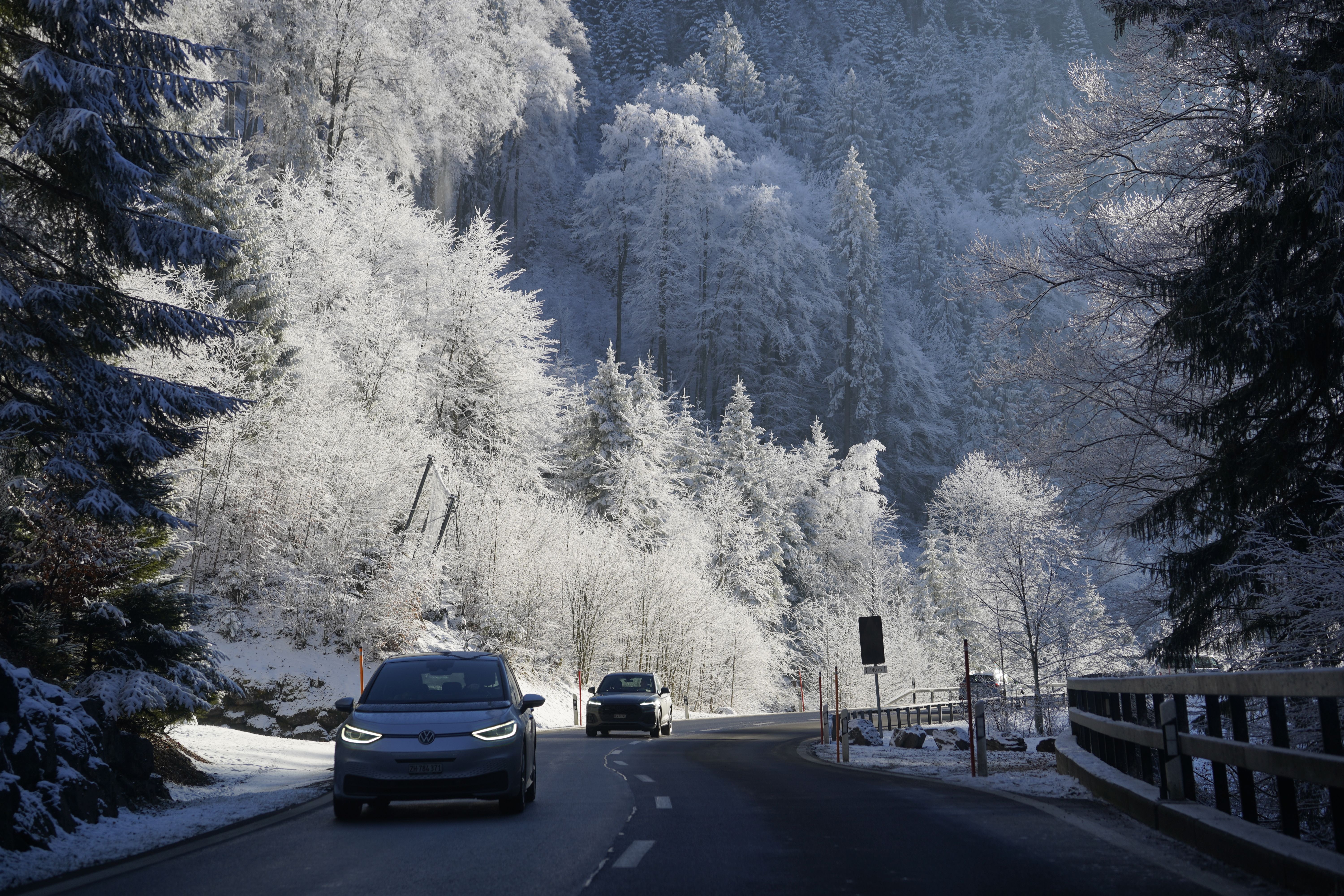 Car driving on a winter road surrounded by snow-covered trees in Engelberg, Obwalden, Switzerland.