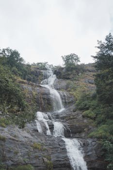 A peaceful waterfall cascading down rocky terrain surrounded by lush greenery.