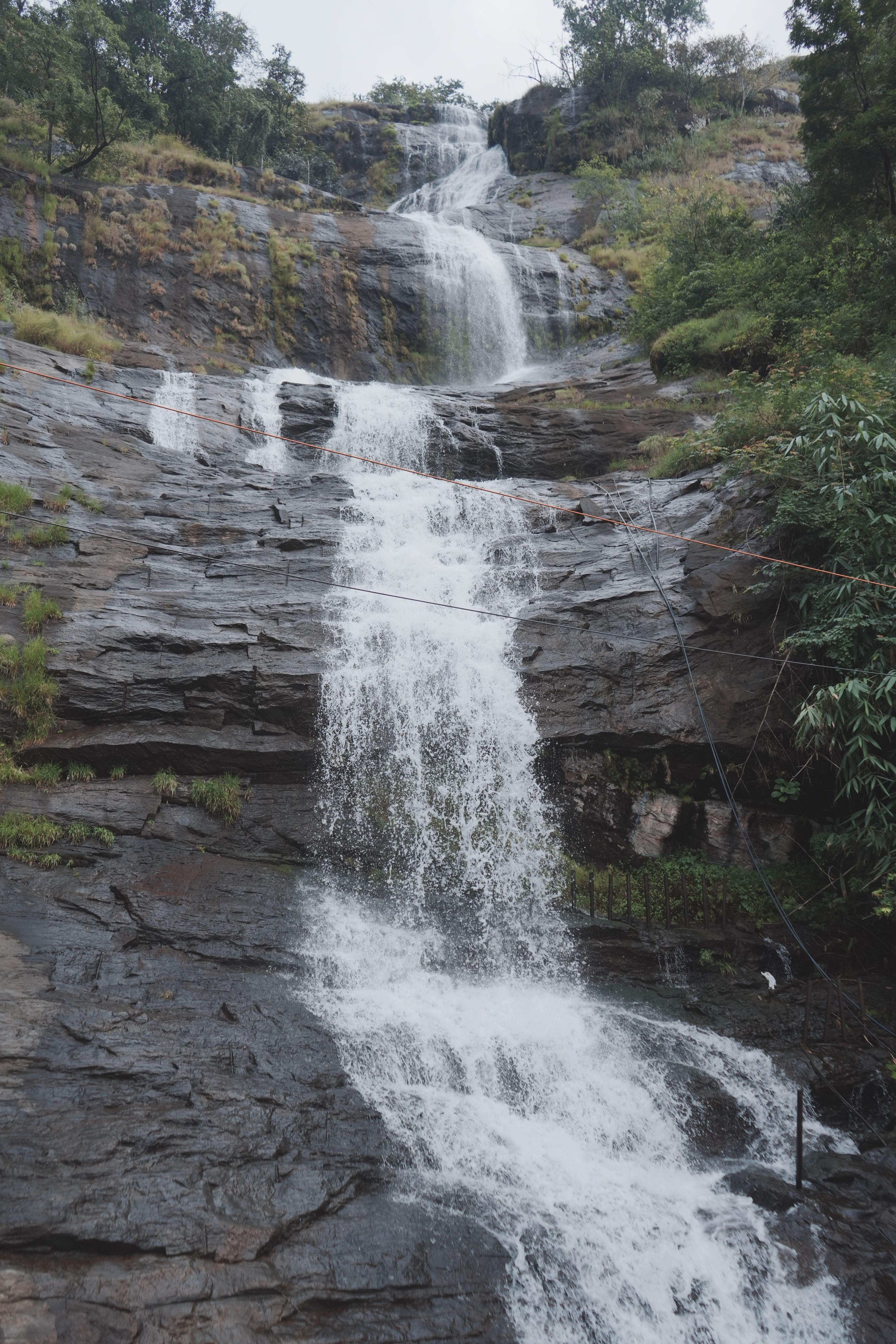 A cascading waterfall amidst a rocky terrain in a vibrant green setting.