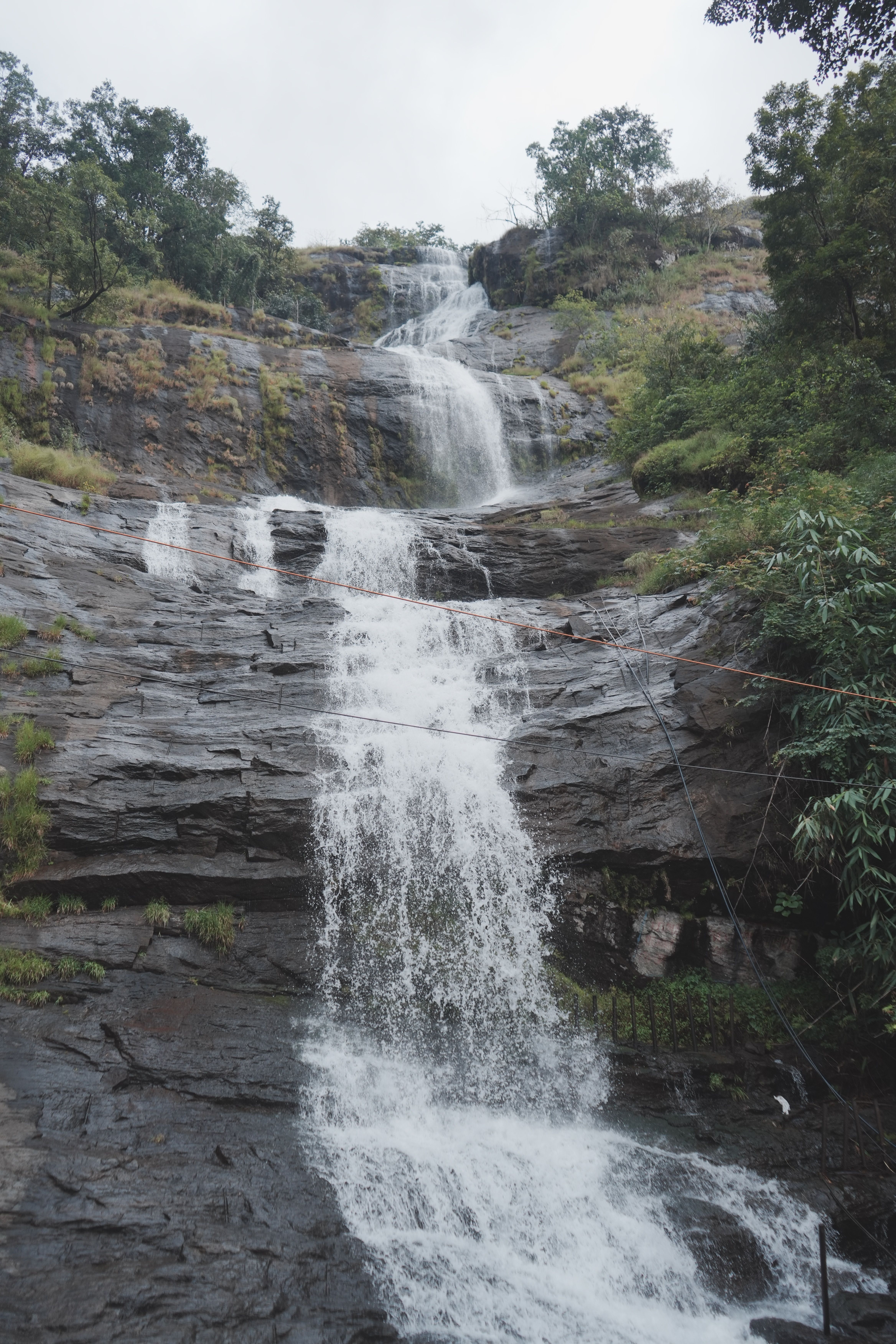 A majestic waterfall cascading down rocky terrain surrounded by lush greenery.