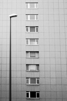 Black and white minimalist view of an urban building facade with windows and a street lamp.