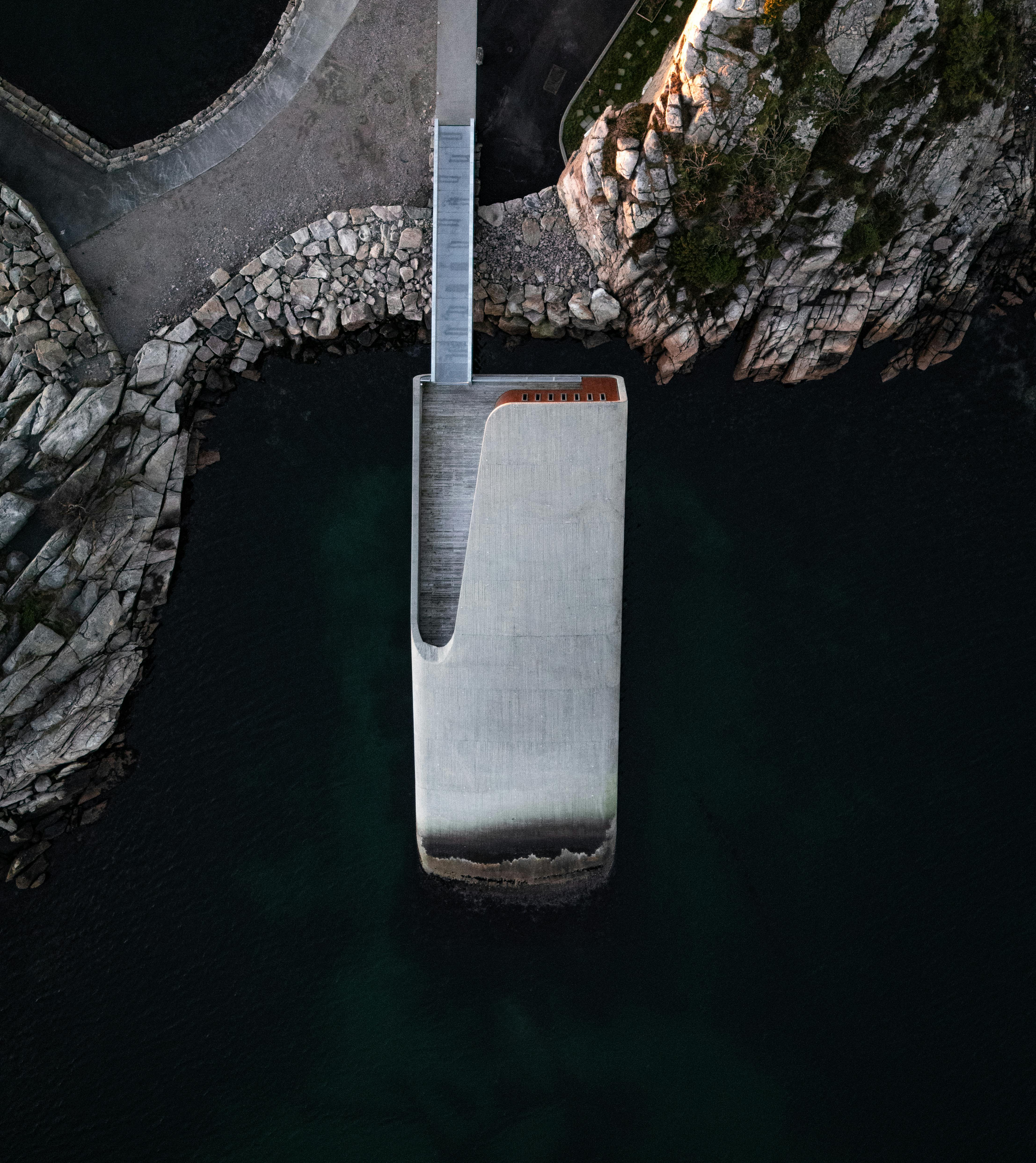 Kostenlos Luftbild, das ein modernes Küstenbauwerk zeigt, das in Felsklippen gebaut und im Meer versenkt ist. Stock-Foto