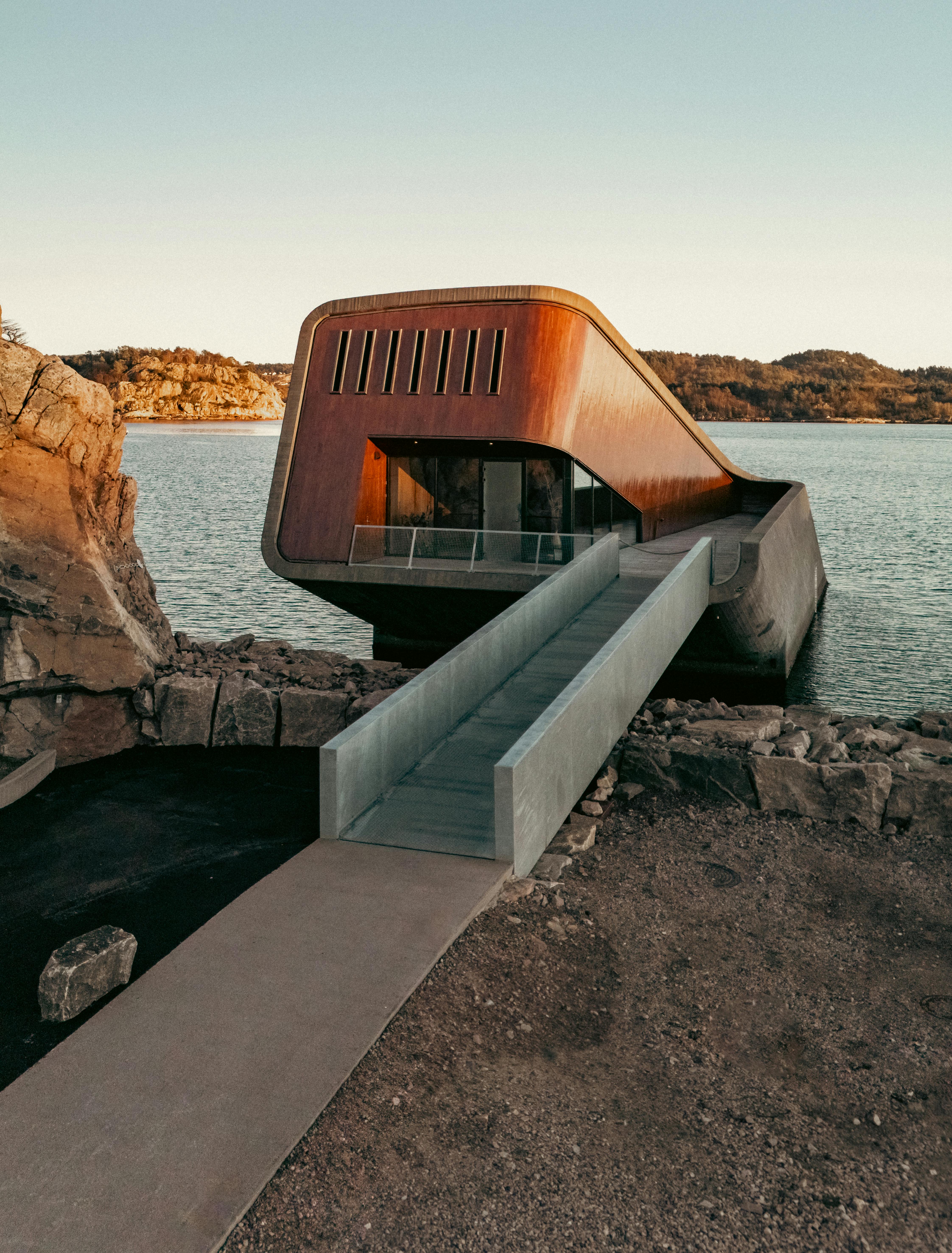 Kostenlos Zeitgenössische Architektur am Wasser vor der Kulisse eines Sonnenuntergangs, die einzigartiges Design und eine ruhige Umgebung präsentiert. Stock-Foto