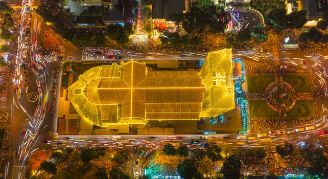 A stunning aerial shot of a cathedral lit by vibrant lights during a festive night.
