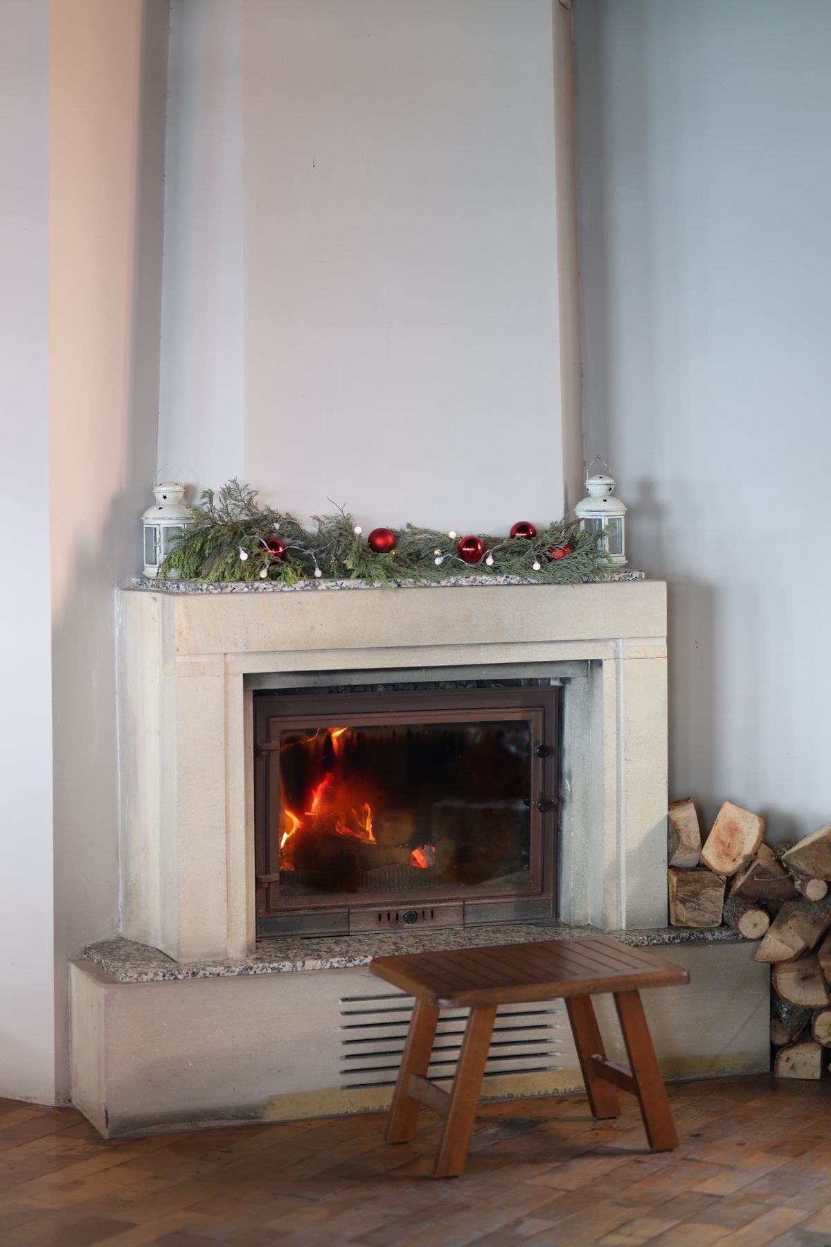 An indoor fireplace dressed for the holidays with fresh greenery draped along the mantel and soft glowing light below