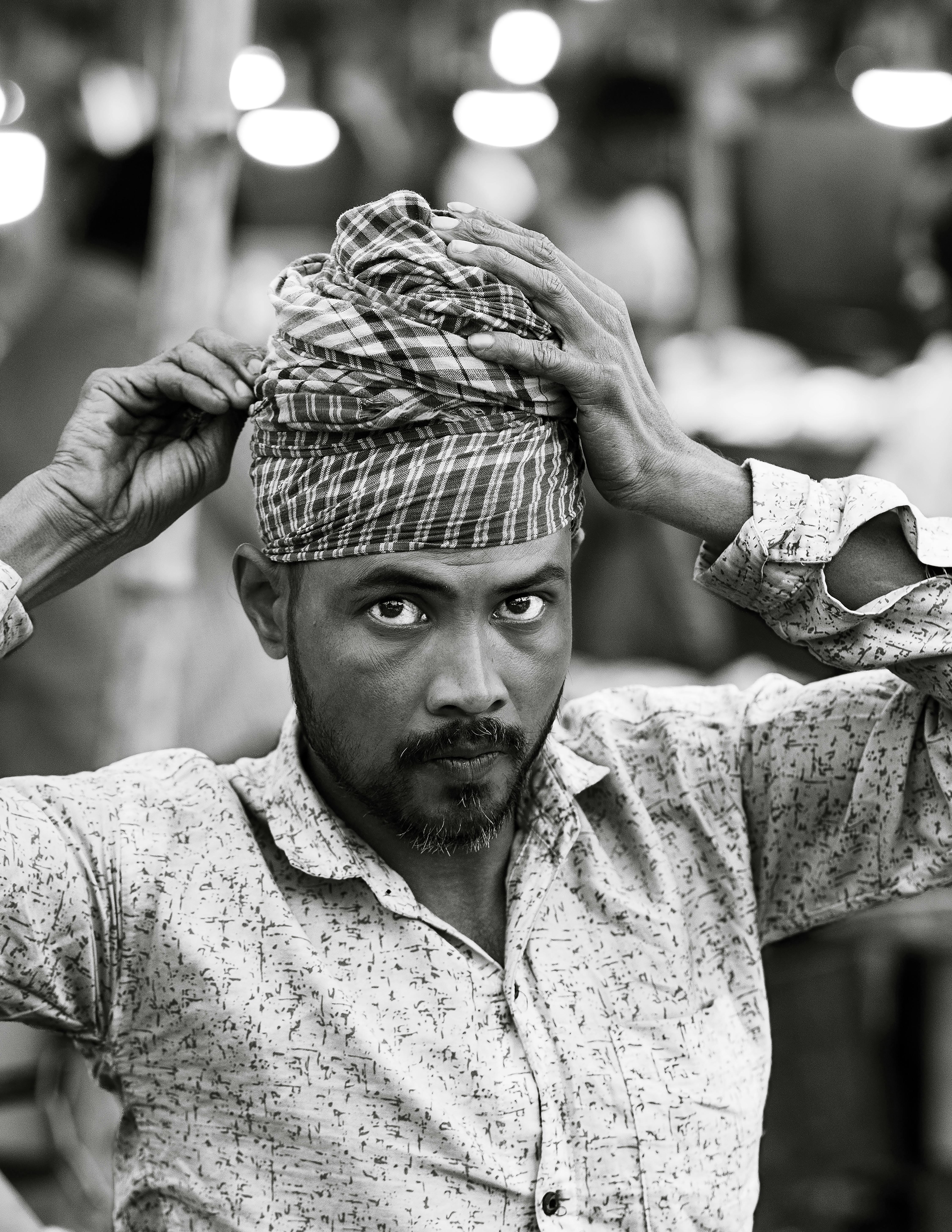 Gratis Retrato en blanco y negro de un hombre ajustándose el pañuelo en la cabeza, capturando la tradición cultural. Foto de stock