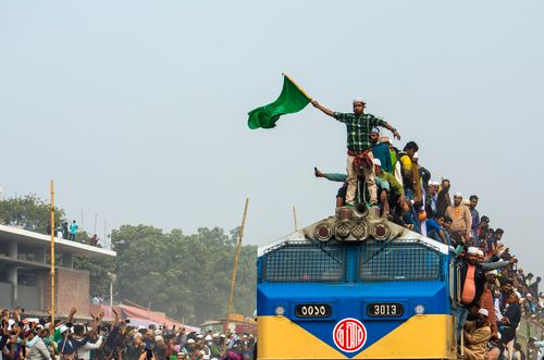 Free A crowded train with people riding on top, one holding a green flag, showcasing a festive or protest atmosphere. Stock Photo