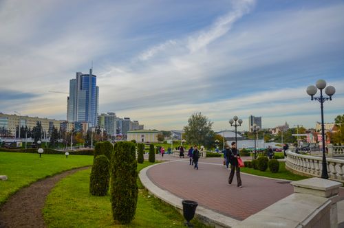 Free A serene city park with people strolling, modern buildings and blue skies. Stock Photo