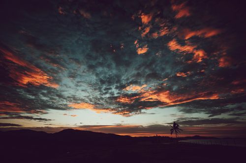 Free Vivid and dramatic sunset over a coastal landscape in Mexico with silhouetted palm trees. Stock Photo