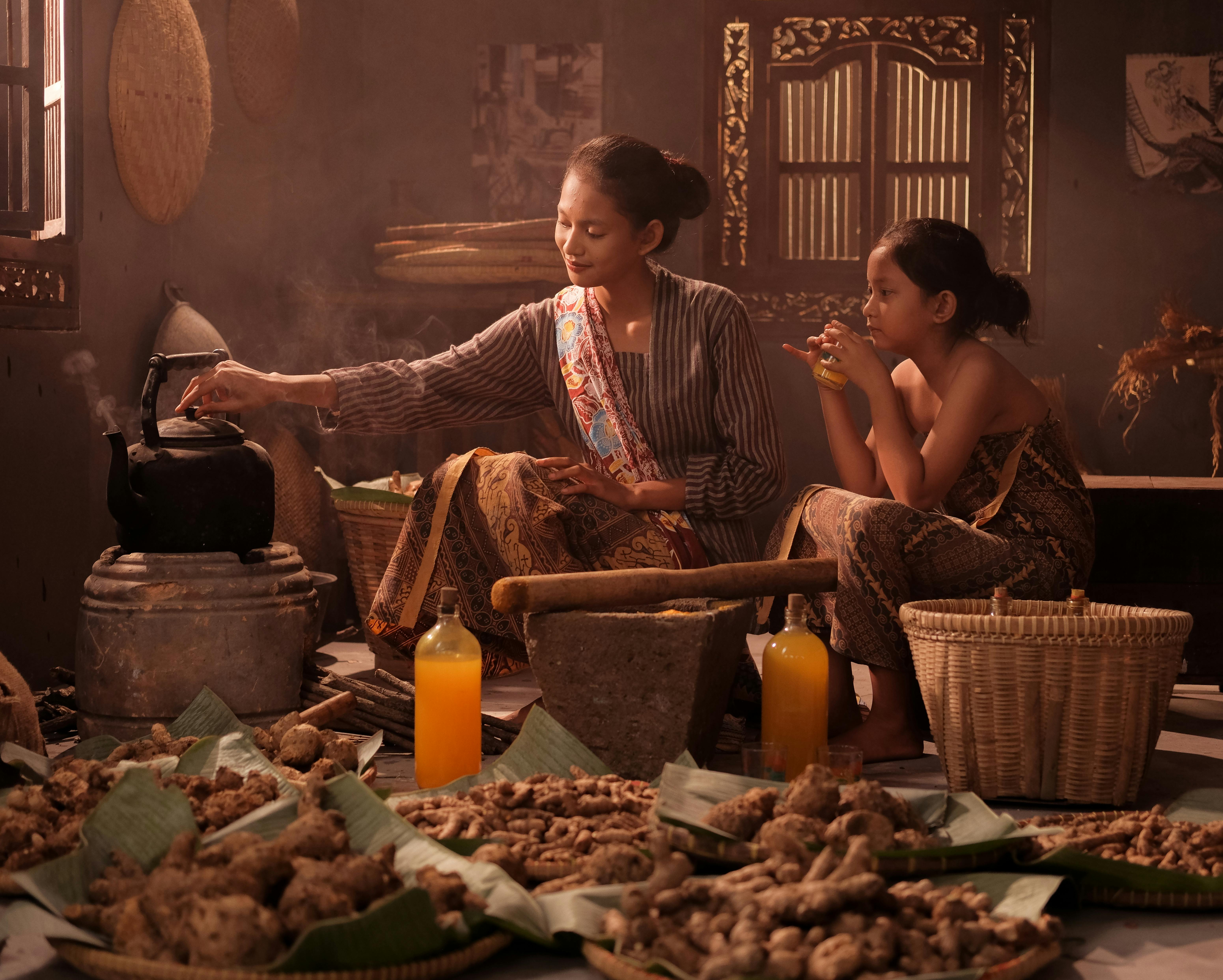 Gratuit Une mère et sa fille en tenue traditionnelle préparent à manger dans une cuisine indonésienne. Photos
