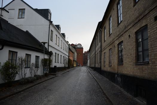 A quiet cobblestone street lined with historic European buildings at sunrise.