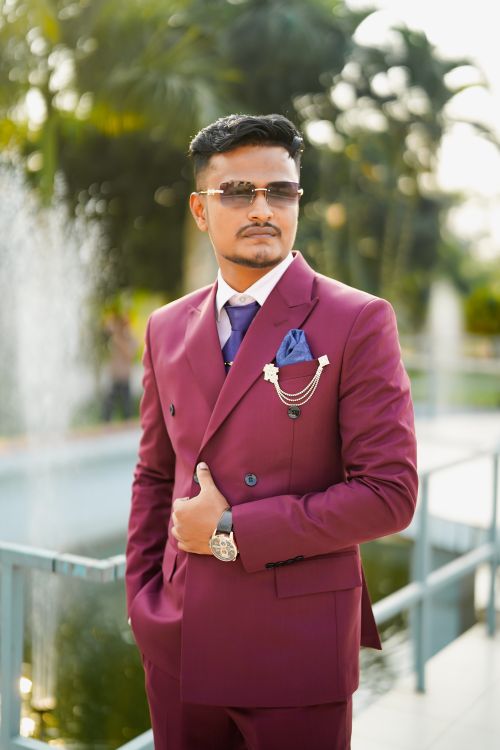 Free A stylish man wears a maroon suit with accessories outdoors, exuding confidence and elegance. Stock Photo