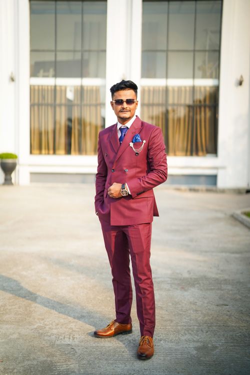 Free Stylish man in maroon suit stands confidently outdoors in front of a modern building. Stock Photo