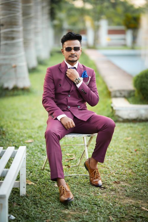 Free Stylish man in burgundy suit sitting on chair outdoors, exuding confidence. Stock Photo