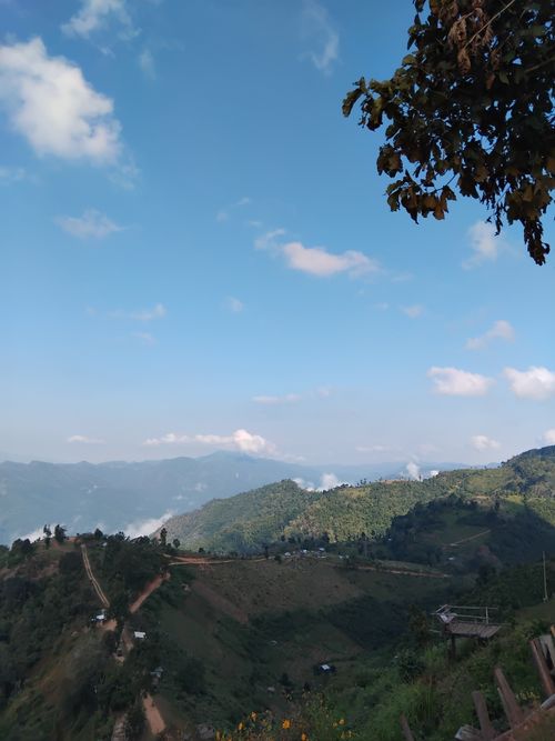 Free Beautiful mountain view under a bright blue sky with scattered clouds, showcasing lush greenery and distant hills. Stock Photo