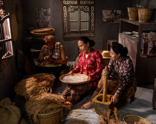 Free Indonesian women in traditional attire prepare food indoors, blending culture and culinary art. Stock Photo