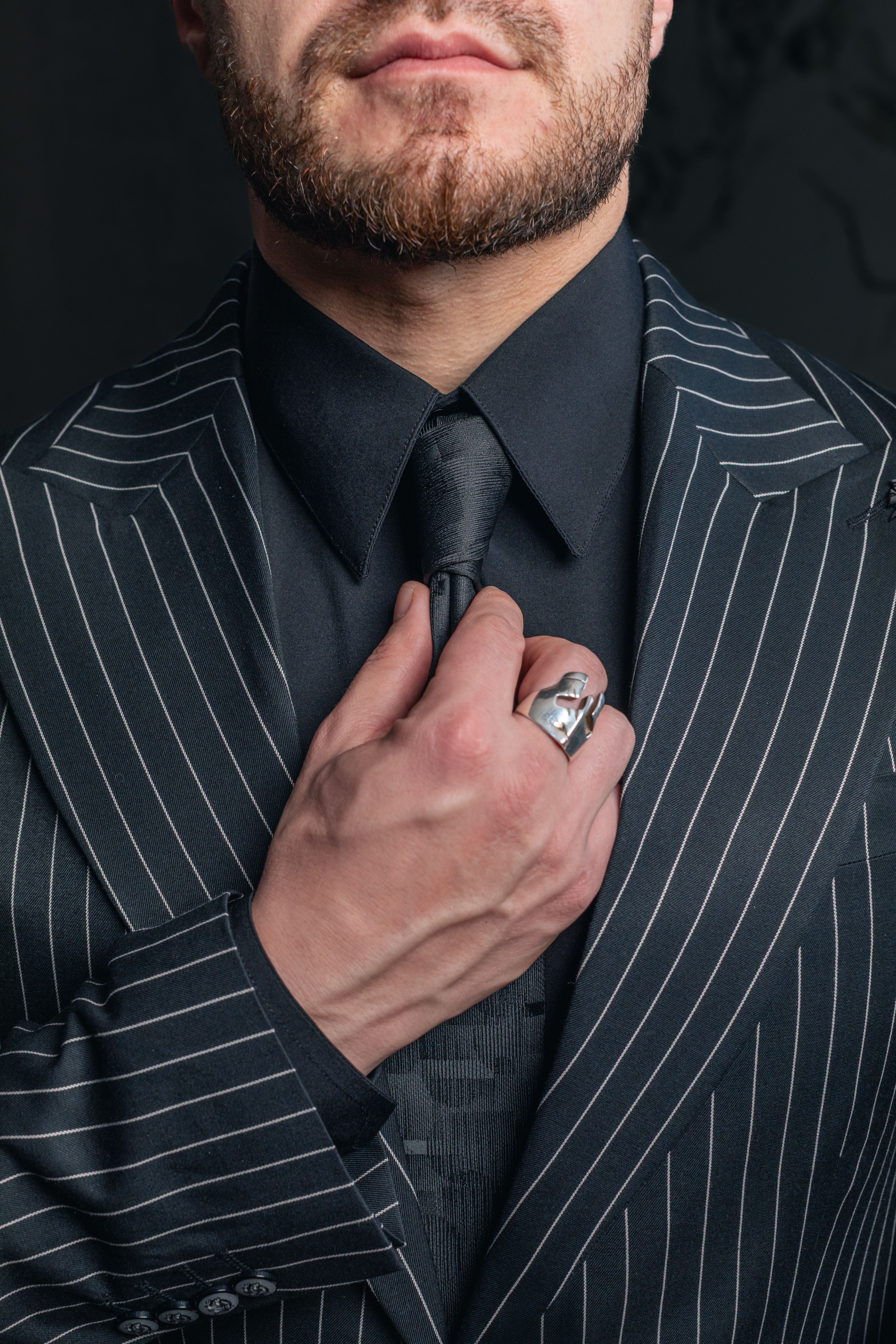 Elegant Man in Pinstripe Suit Adjusting Tie