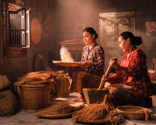 Free Women in traditional attire preparing rice indoors, showcasing cultural heritage. Stock Photo