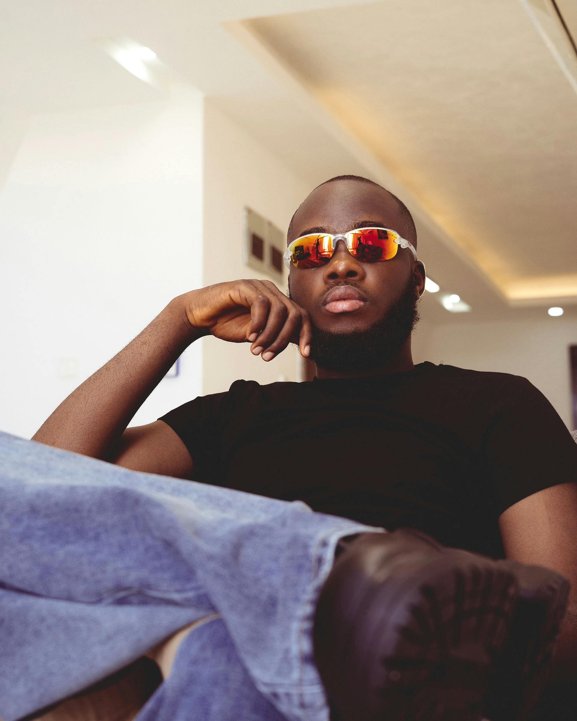 De franc Home elegant amb ulleres de sol relaxant-se a l'interior, desprenent confiança. Foto d'estoc