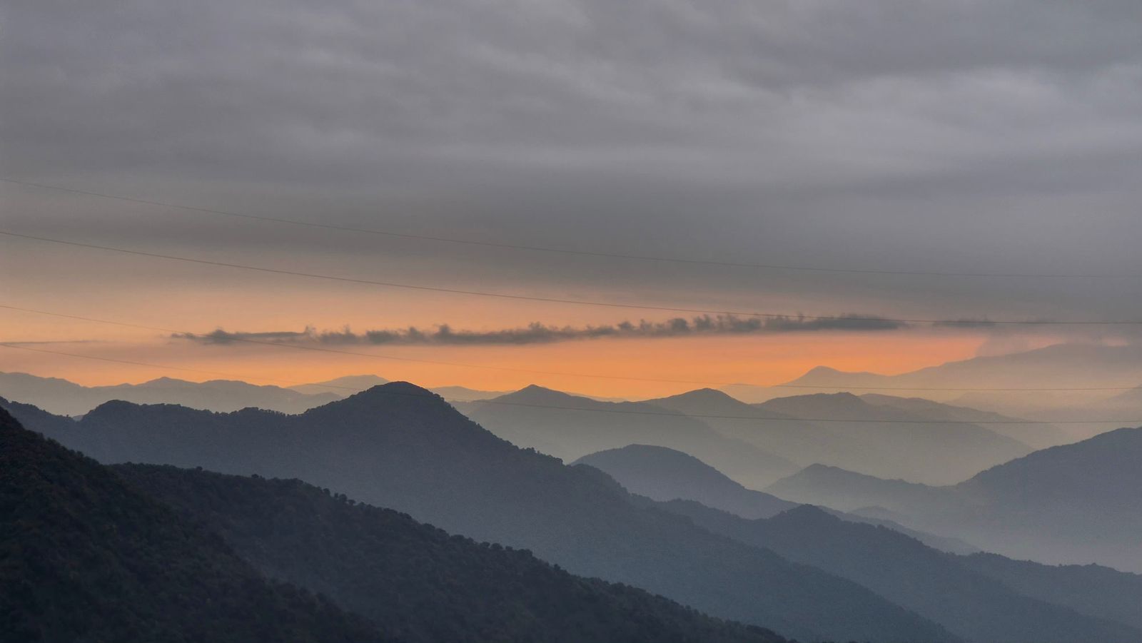 Sunset over the ranges at Zuluk in East Sikkim, layered blue ridges fading back under an orange band of sky