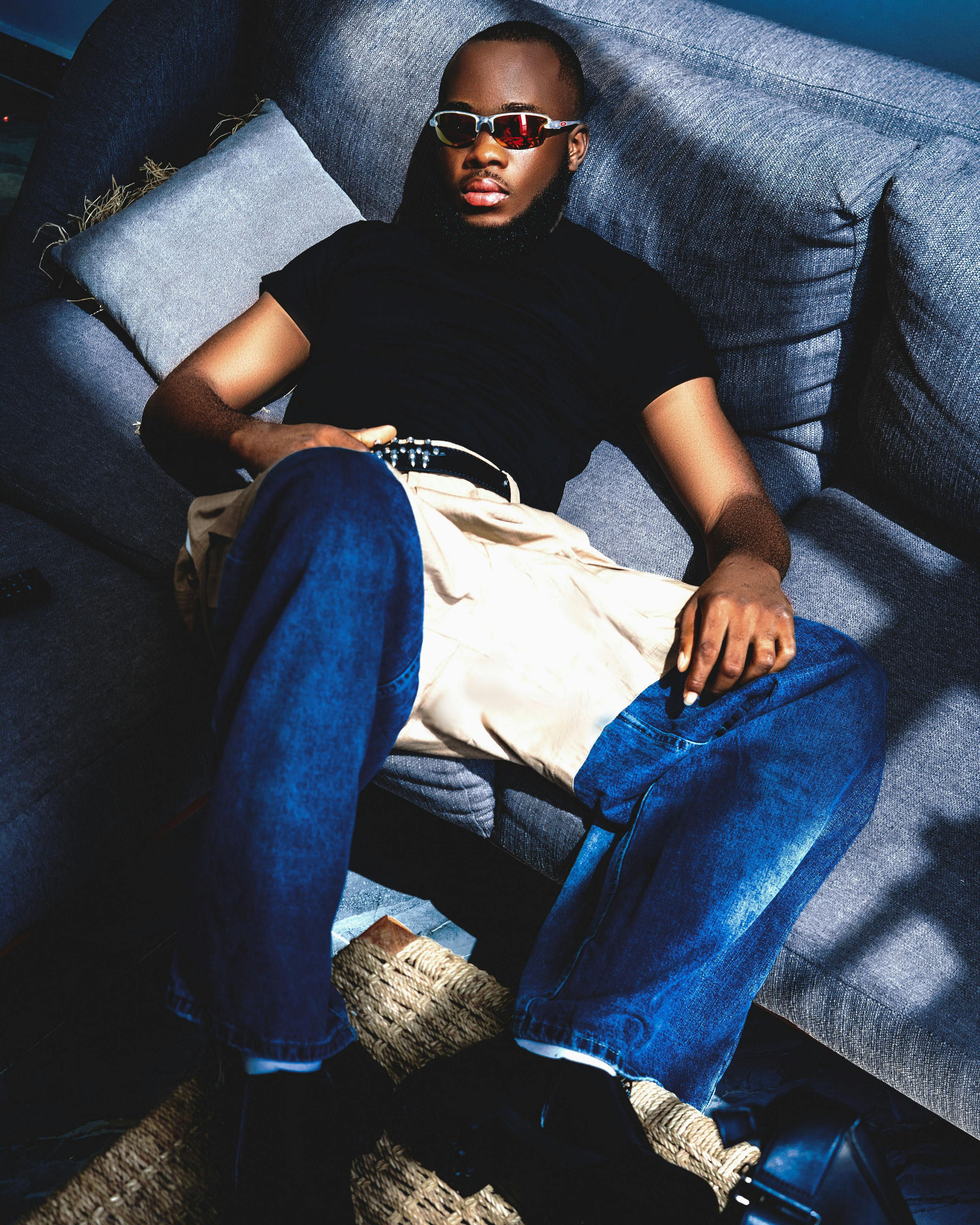 Trendy man with sunglasses relaxing on a sofa in a stylish modern setting.