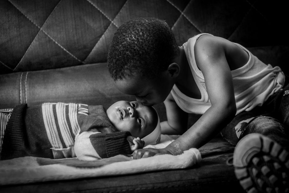 Irmão mais velho beijando com carinho o bebê recém-nascido