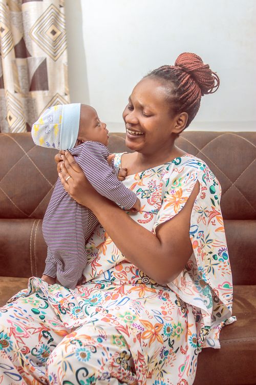 Free A smiling mother holds her baby indoors, capturing a joyful family moment. Stock Photo