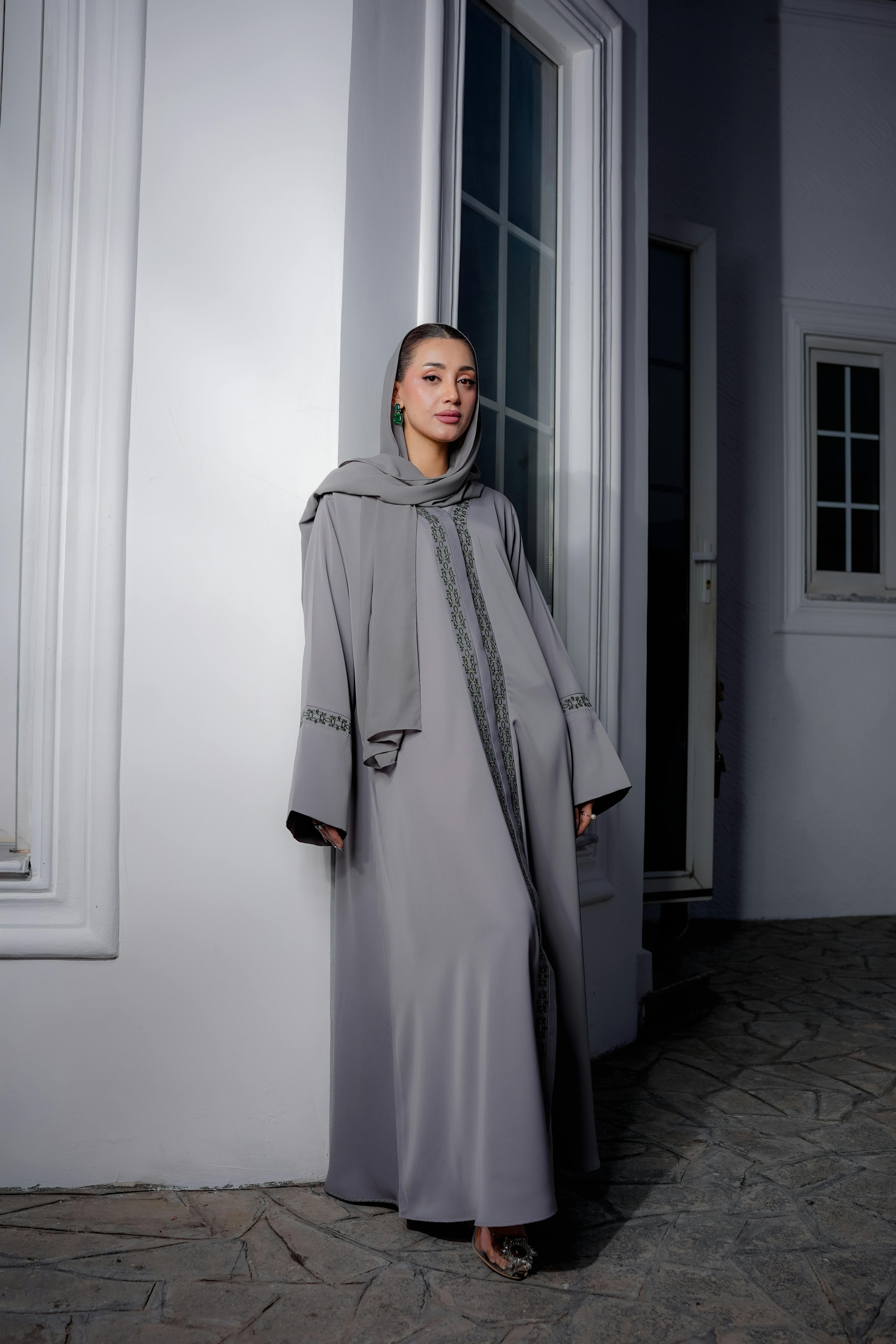 Gratis Una mujer elegante con una abaya gris se destaca elegantemente en un interior moderno. Foto de stock