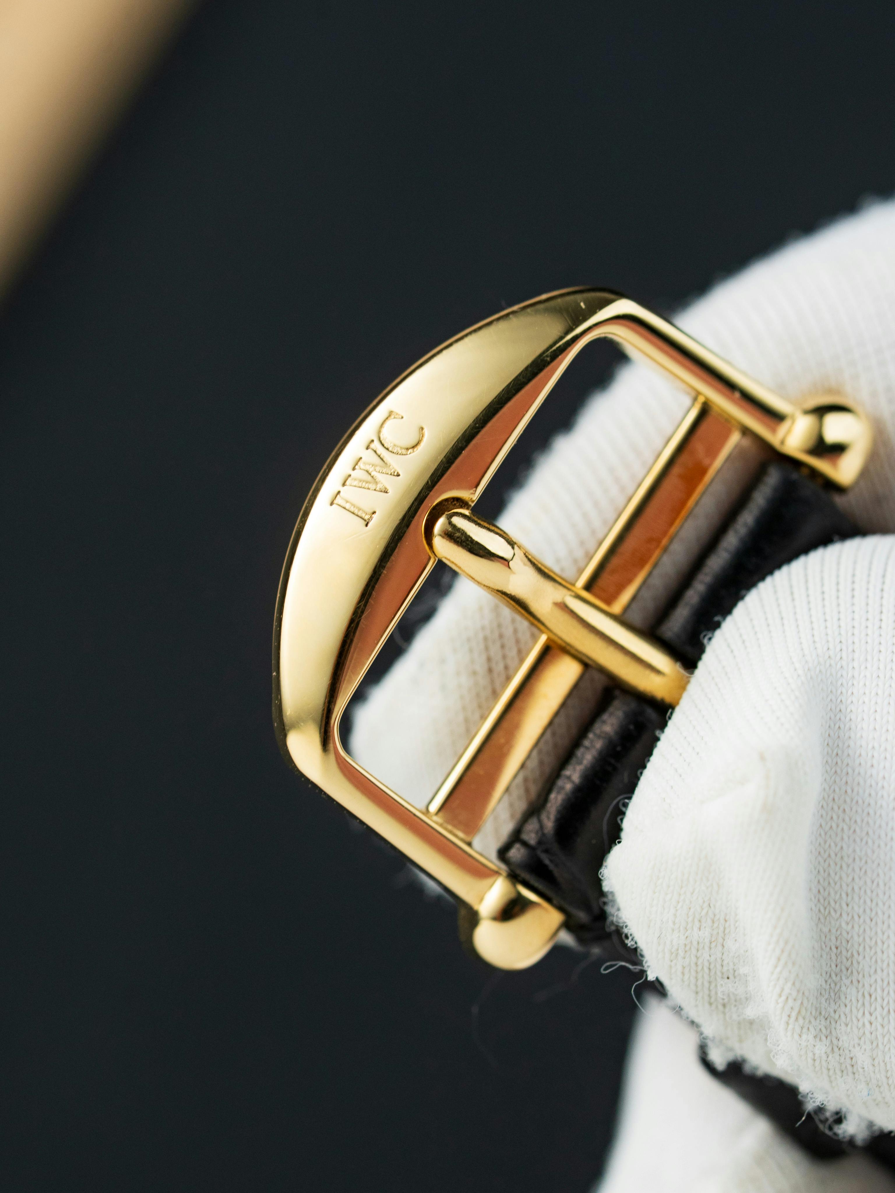 De franc Primer pla d'una sivella de rellotge d'or subjectada per una mà enguantada, que mostra artesania de luxe. Foto d'estoc