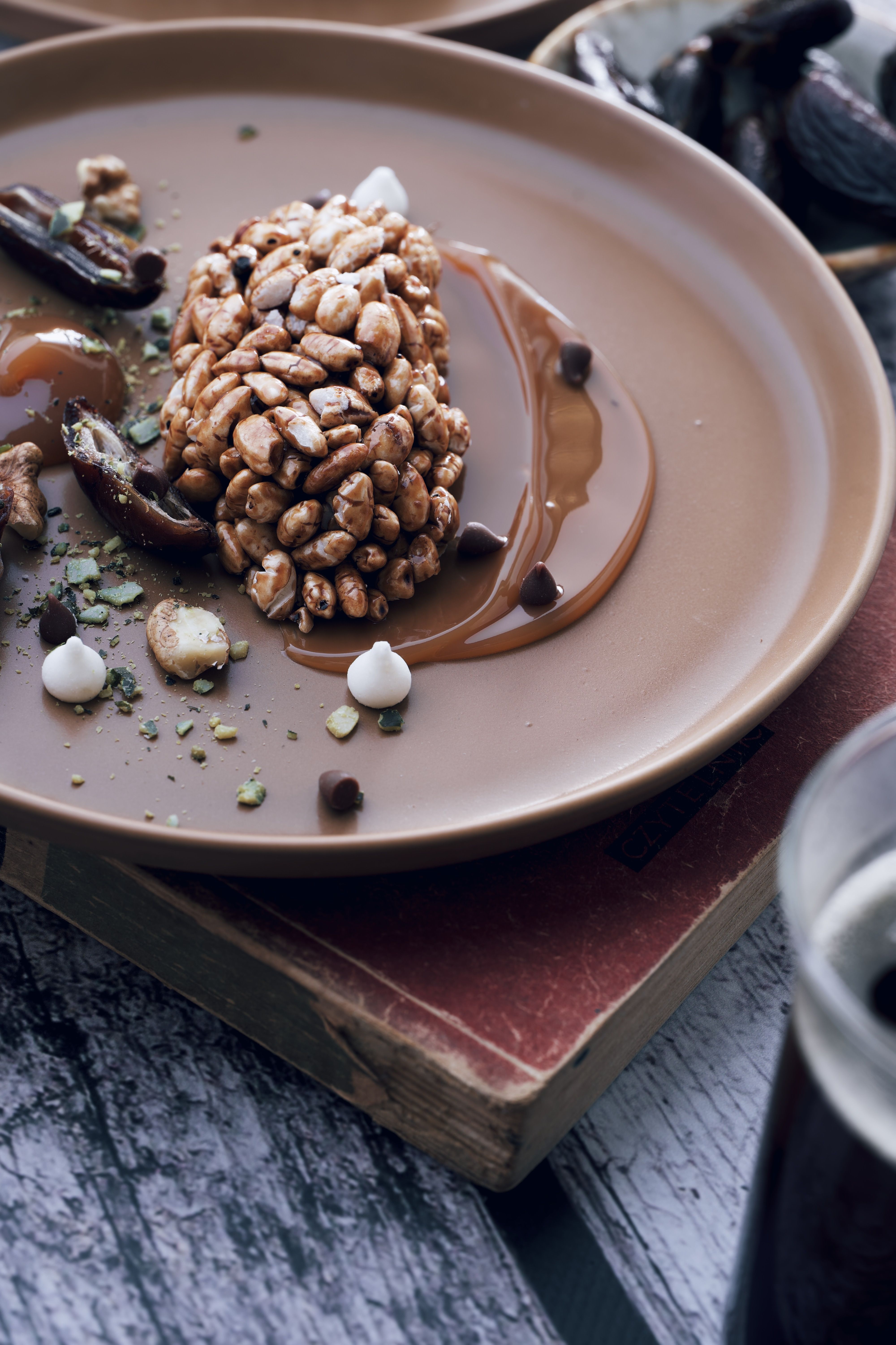 Elegant dessert plate with chocolate drizzle and nuts in a rustic setting.