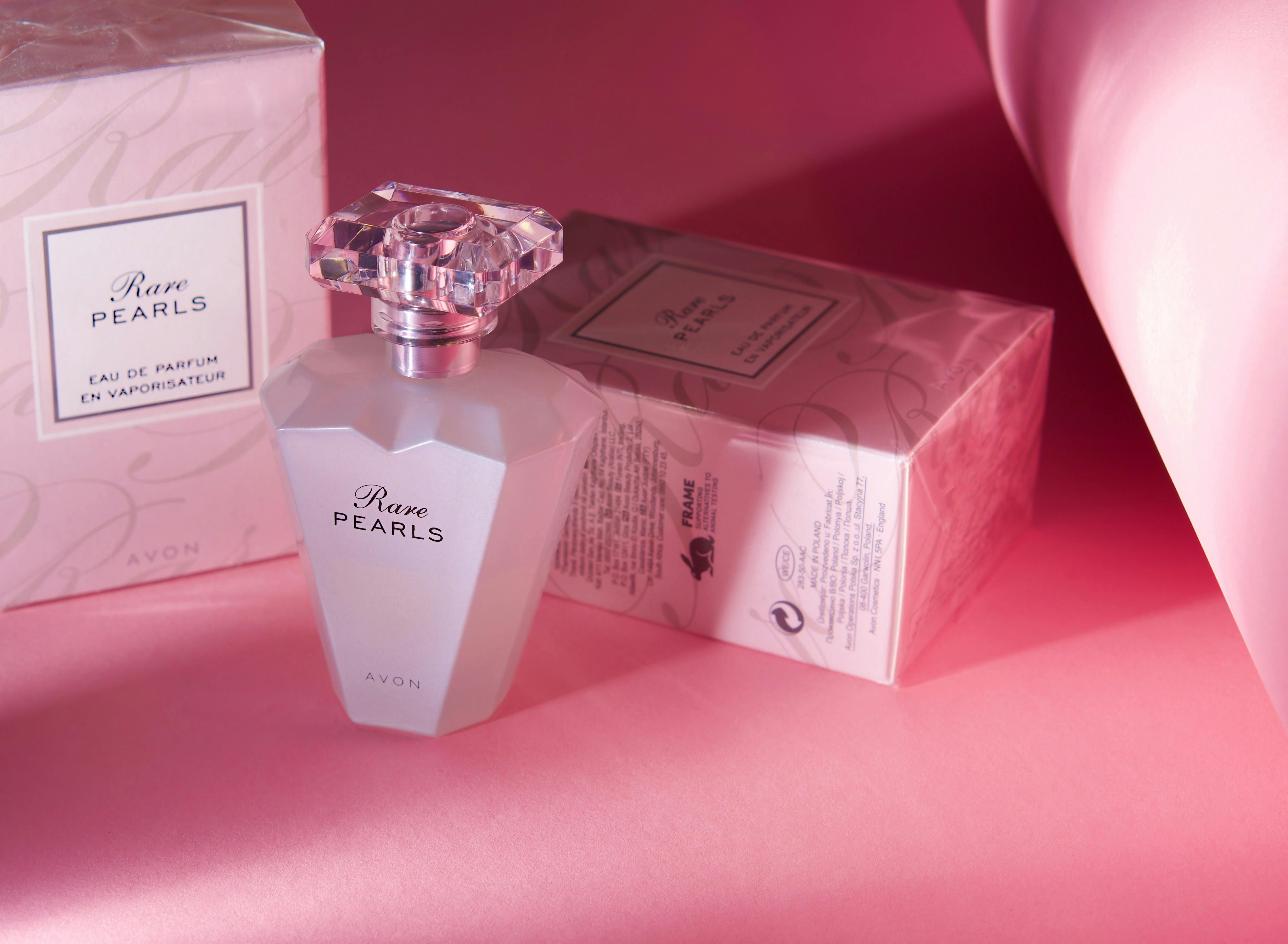 De franc El perfum Chic Avon Rare Pearls es presenta sobre un elegant fons rosa, que destaca el luxe i l'elegància. Foto d'estoc