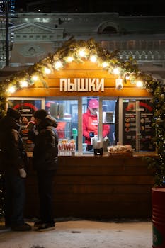 A warmly lit donut stall at a winter night market, with people enjoying hot treats.