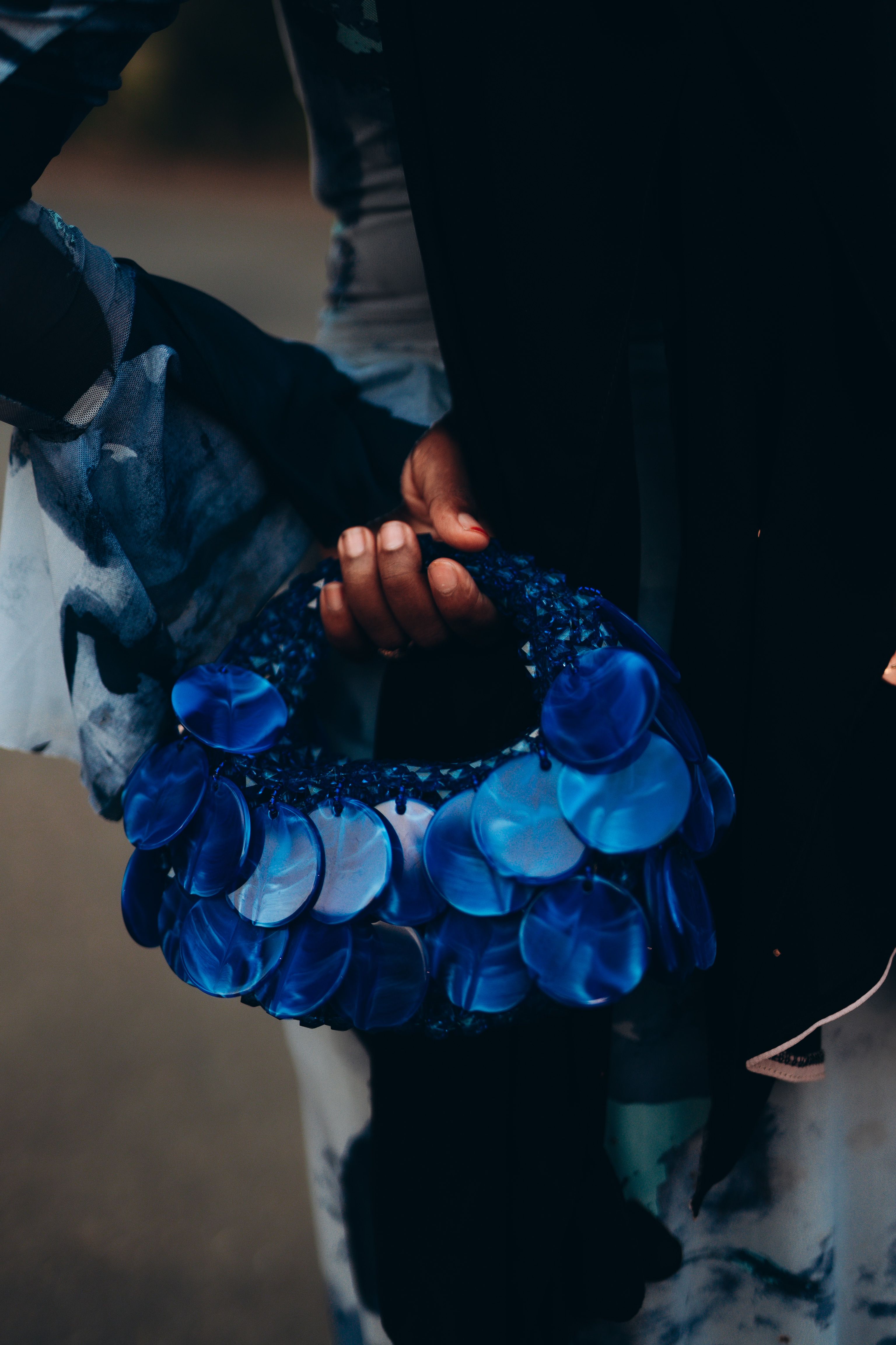 Close-up of a blue circular handbag held by a person with colorful attire, stylish and artistic.
