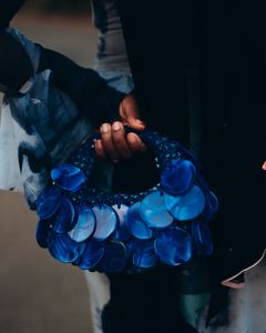 Close-up of a blue circular handbag held by a person with colorful attire, stylish and artistic.