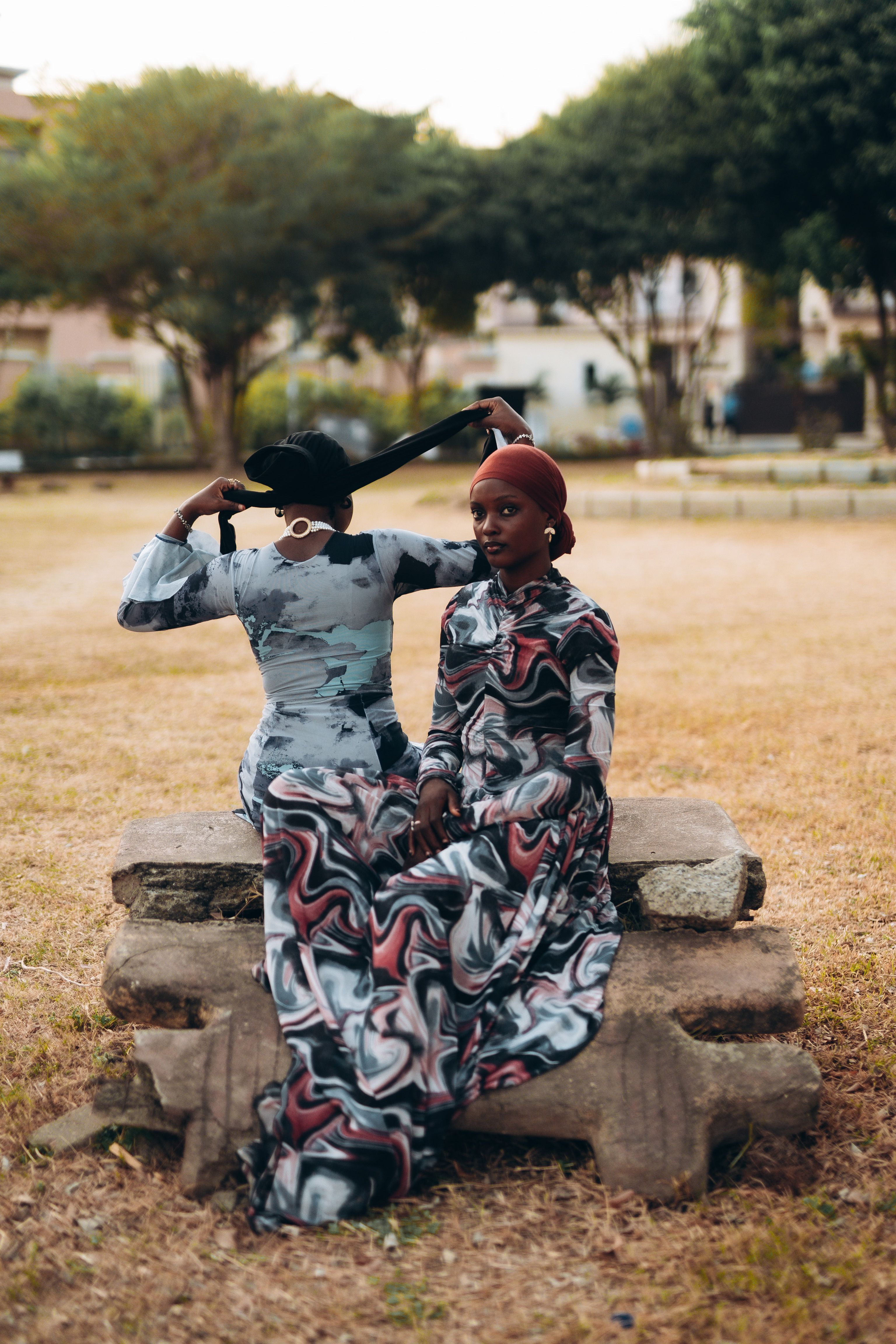 Two Women in Patterned Dresses Seated Outdoors · Free Stock Photo
