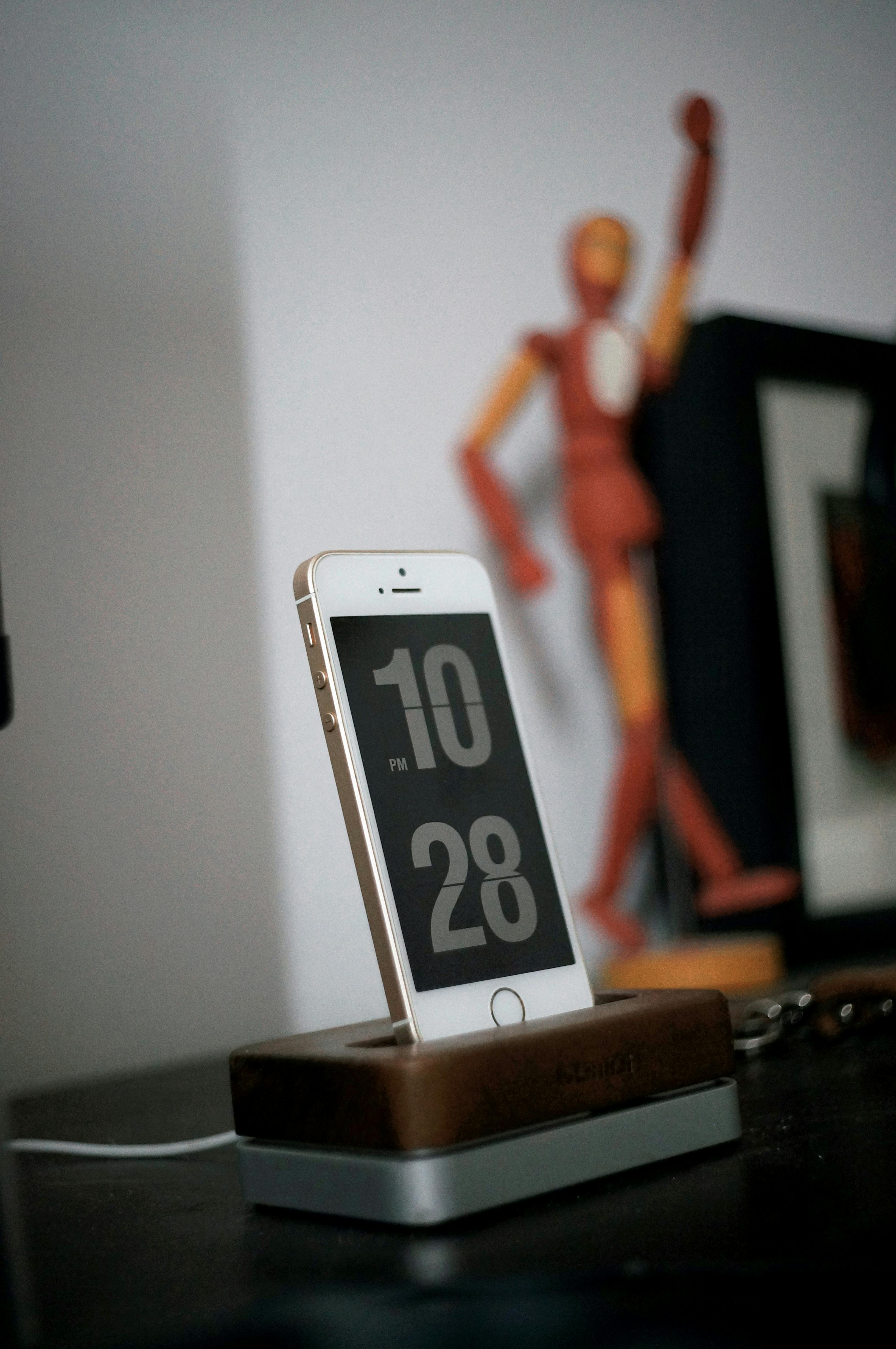 grátis Smartphone em base de madeira com relógio digital à mostra, decoração elegante para casa. Foto profissional