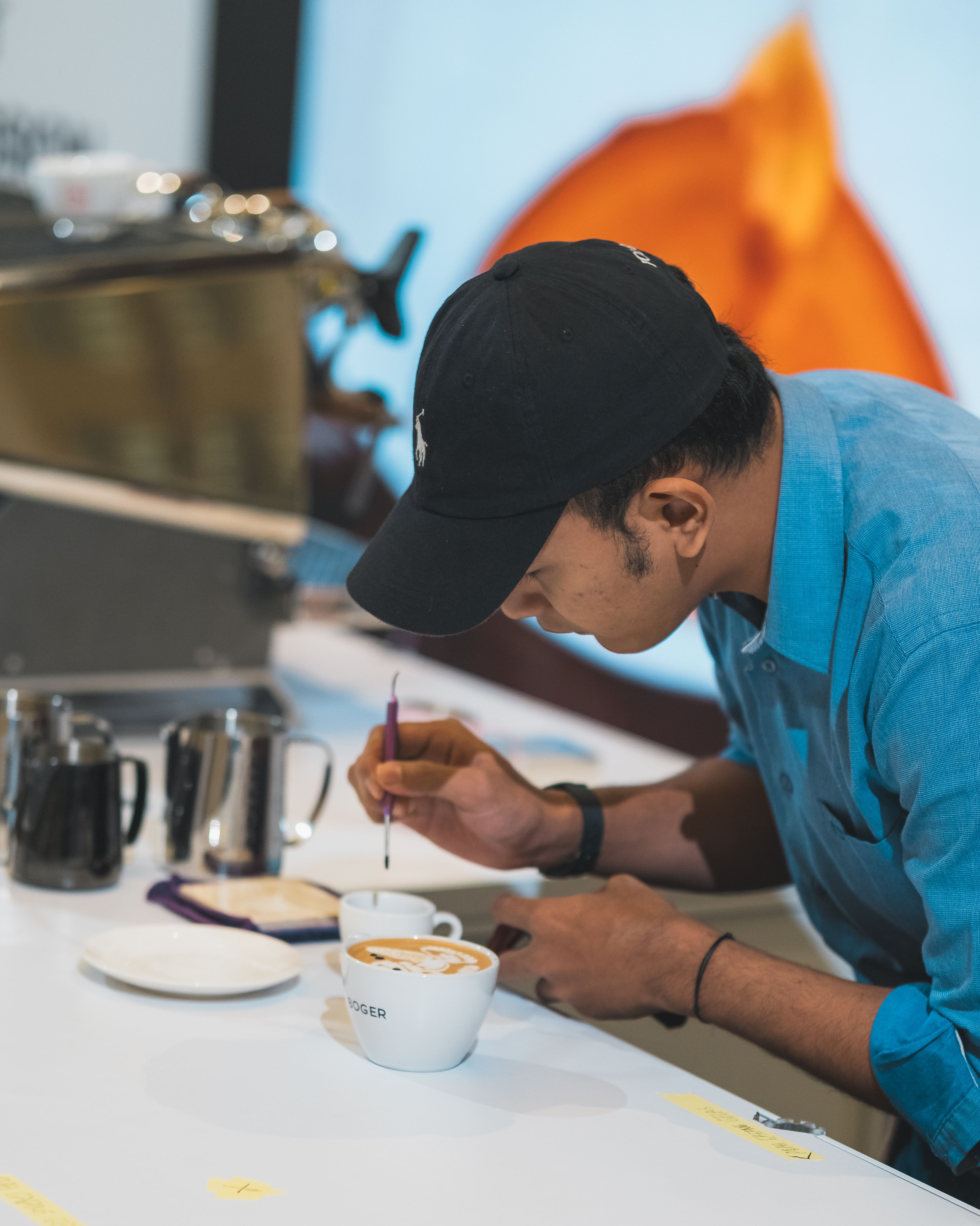 Barista crafting intricate latte art on coffee in a bustling cafe setting.
