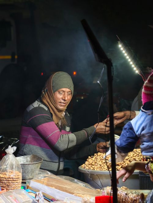 Free A street vendor sells peanuts in a bustling night market in New Delhi, India. Stock Photo