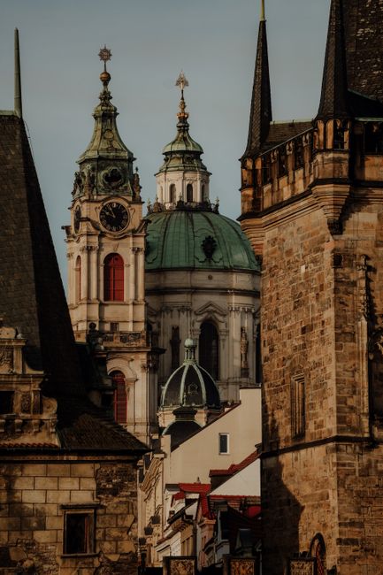 Captivating view of Prague's historic church towers and stone buildings at sunset.