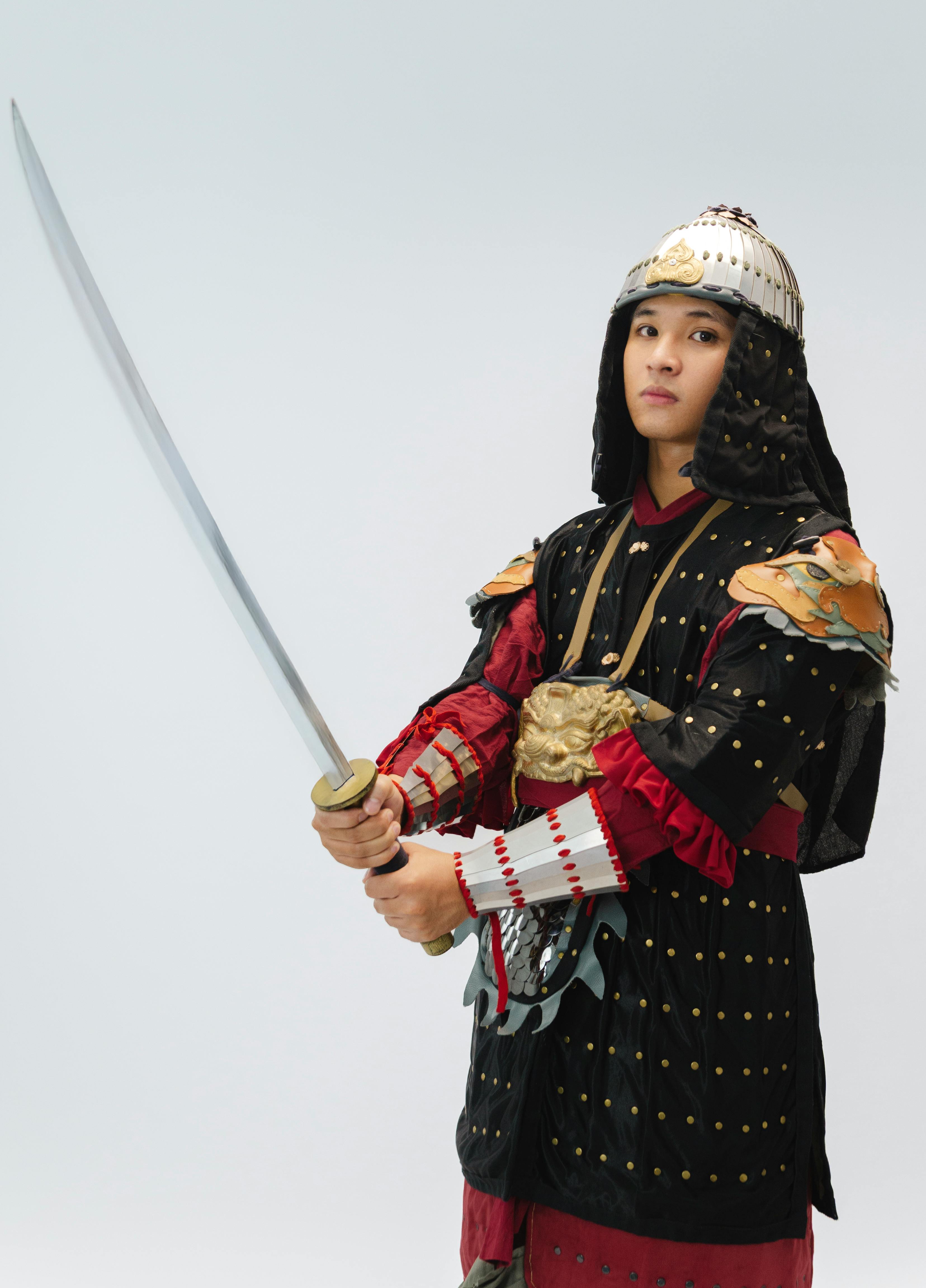 Portrait of a young warrior wearing traditional samurai armor holding a katana sword against a white background.
